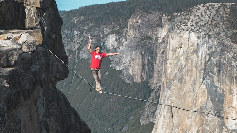 person standing on rope near mountain cliff